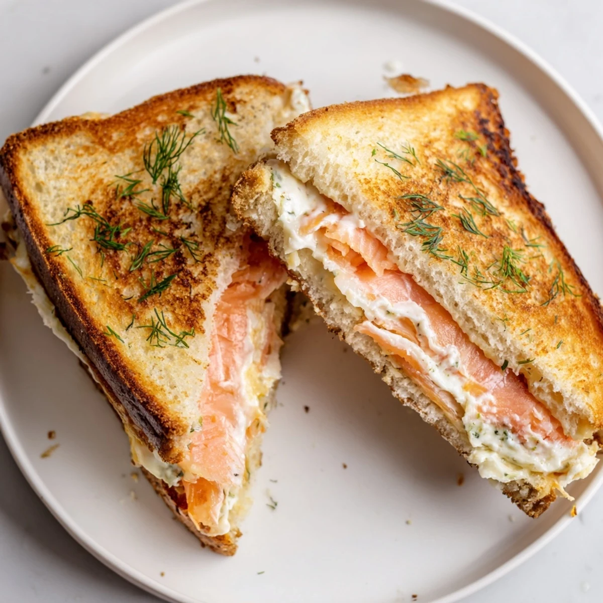 Golden-brown Smoked Salmon Grilled Cheese, oozing melted cheese and flaky salmon, on a plate ready to eat.