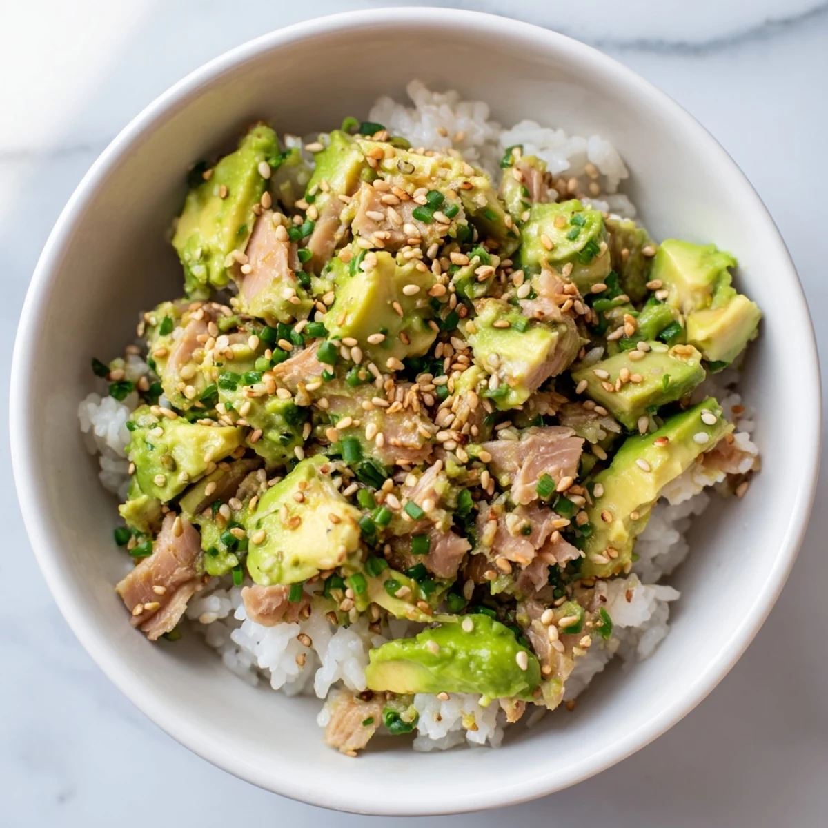 Vibrant Tuna Avocado Rice Bowl garnished with scallions, drizzled with a savory soy-sesame dressing for a fresh, satisfying meal.  