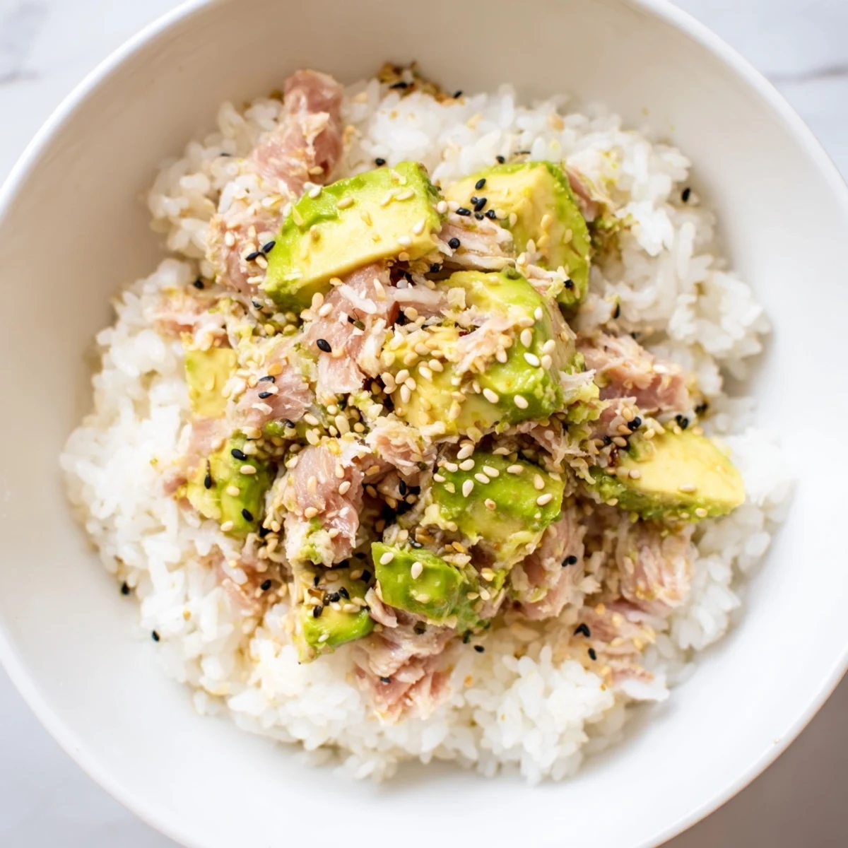 Creamy avocado and tender tuna chunks rest on fluffy jasmine rice, topped with crisp cucumber and toasted sesame seeds.  