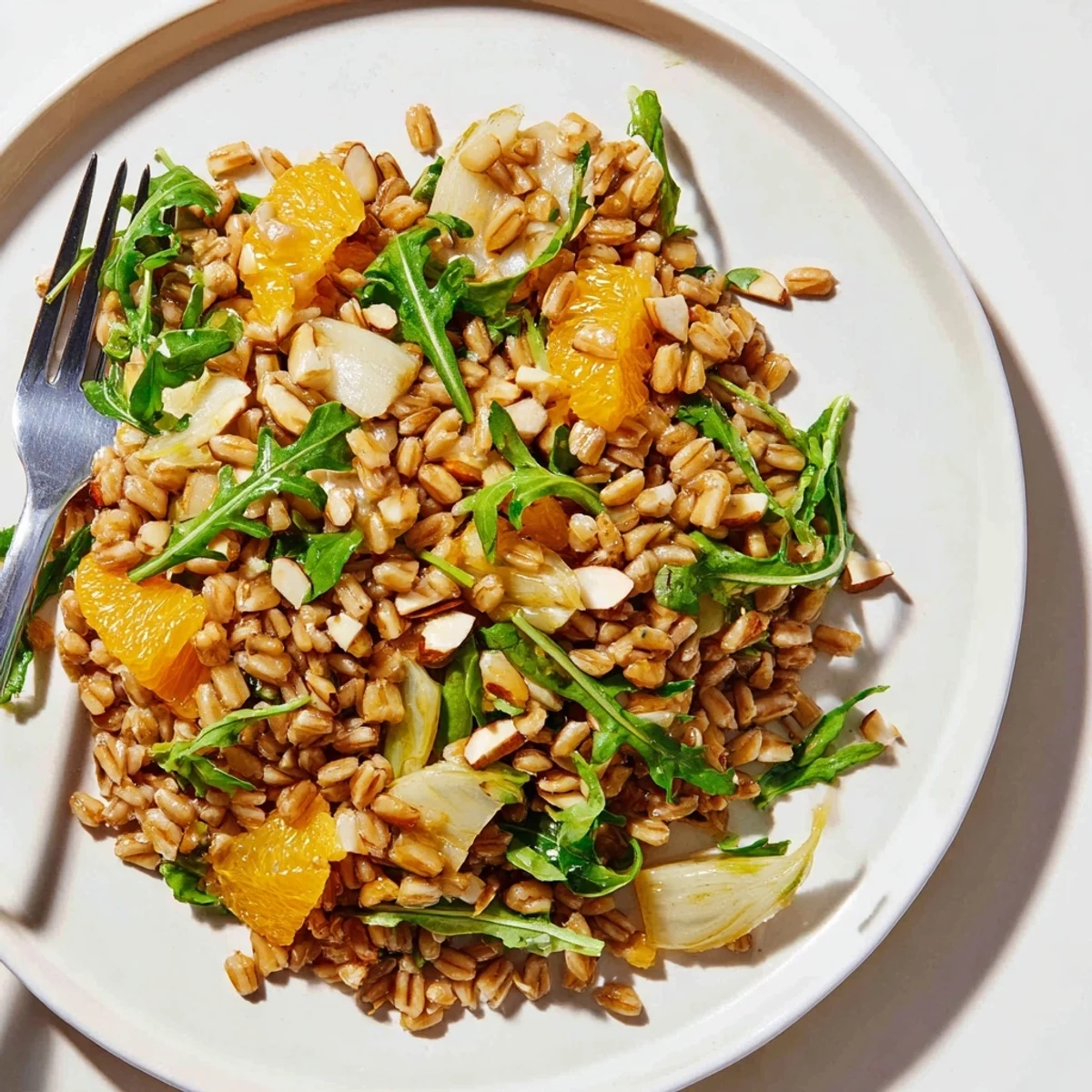 Healthy Farro salad with fennel, oranges, and almonds for a Mediterranean lunch, garnished with fresh parsley and arugula.
