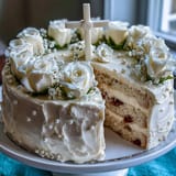 Delicate vanilla sponge cake decorated with white fondant roses and a symbolic cross topper for First Communion