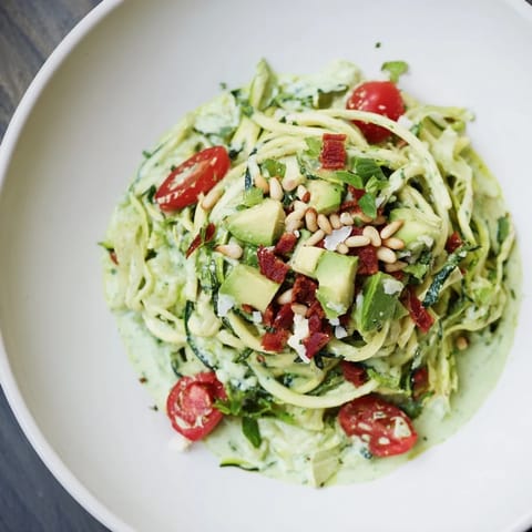 Bright, flavorful Green Goddess Zoodle Pasta, tossed with chopped tomatoes and creamy avocado, ready to serve.