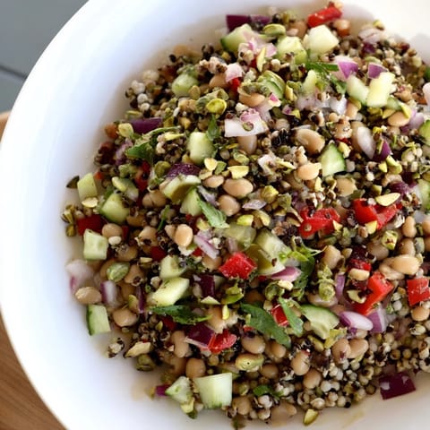 A refreshing close-up of the finished Dense Bean Salad, featuring roasted pistachio garnish.
