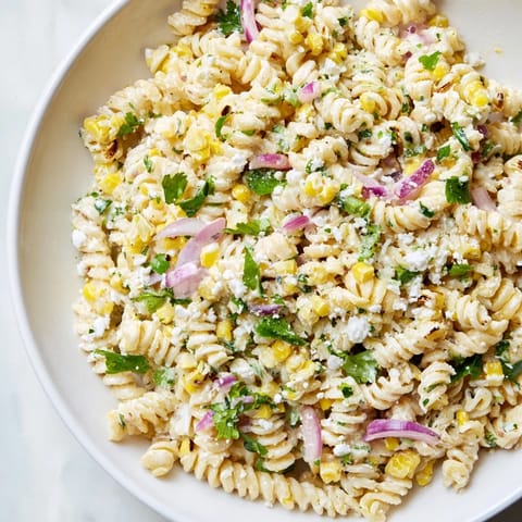 This Creamy Street Corn Pasta Salad showcases a chilled bowl of pasta, bursting with fresh, colorful ingredients.