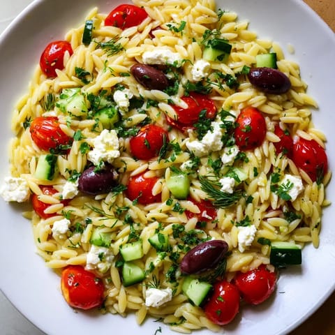 Colorful Greek orzo salad featuring orzo pasta, Kalamata olives, and zesty lemon-oregano dressing, ready to serve.