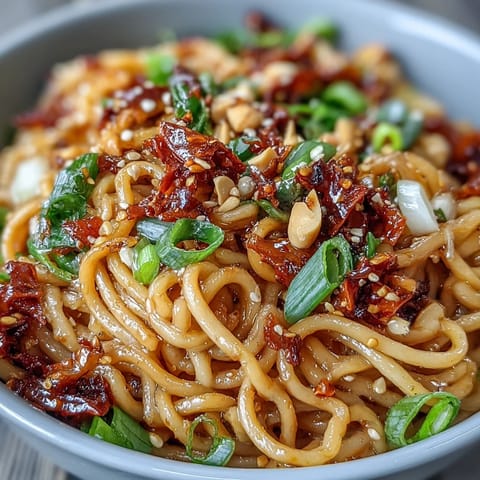 Chewy wheat noodles tossed with aromatic garlic, chili crisp, and fresh vegetables for a bold, umami-packed vegetarian dish.  