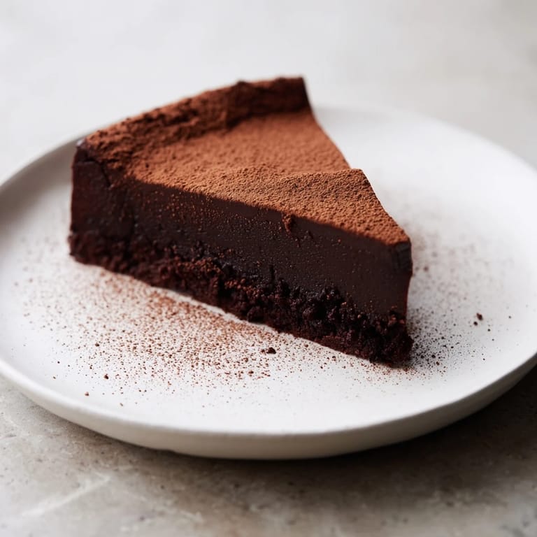 Perfectly baked, this decadent flourless chocolate cake looks moist and ready to enjoy with whipped cream.