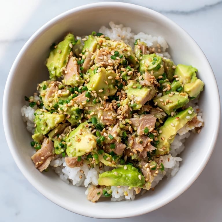 Vibrant Tuna Avocado Rice Bowl garnished with scallions, drizzled with a savory soy-sesame dressing for a fresh, satisfying meal.  