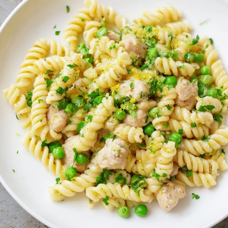 Family-style platter of Garlic Butter Chicken & Pea Pasta, garnished with Parmesan and lemon zest, ready to serve on a rustic table.