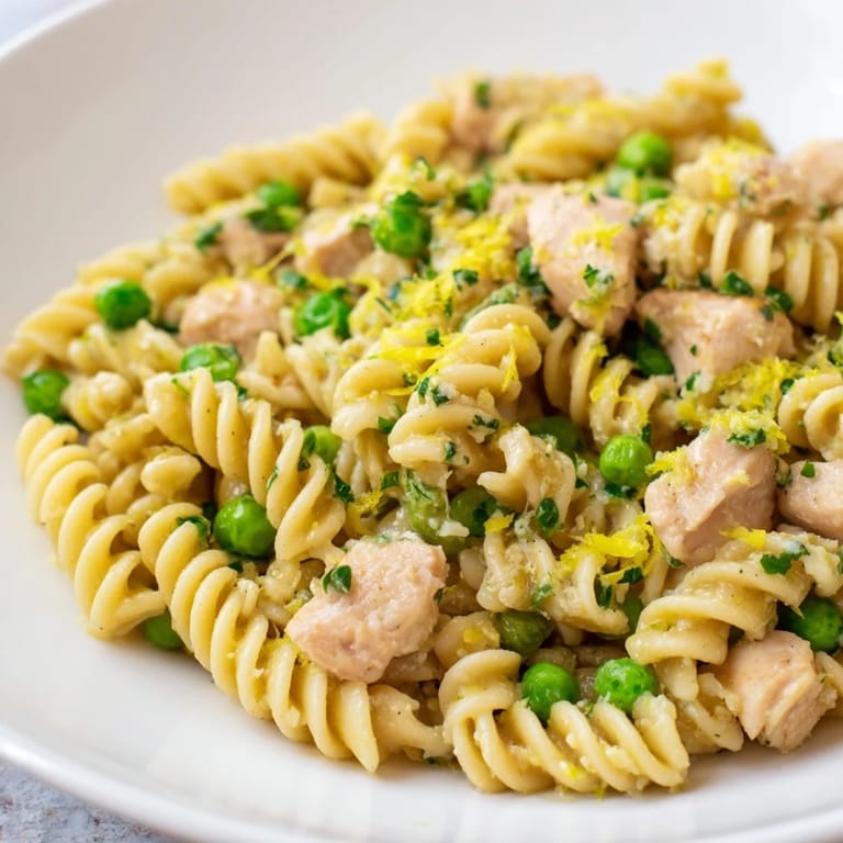 A close-up of Garlic Butter Chicken & Pea Pasta shows a glossy, garlic butter sauce coating every twist of pasta, finished with fresh parsley.  