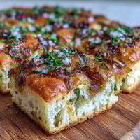 Chewy sourdough focaccia bread topped with golden caramelized onions and flaky sea salt.